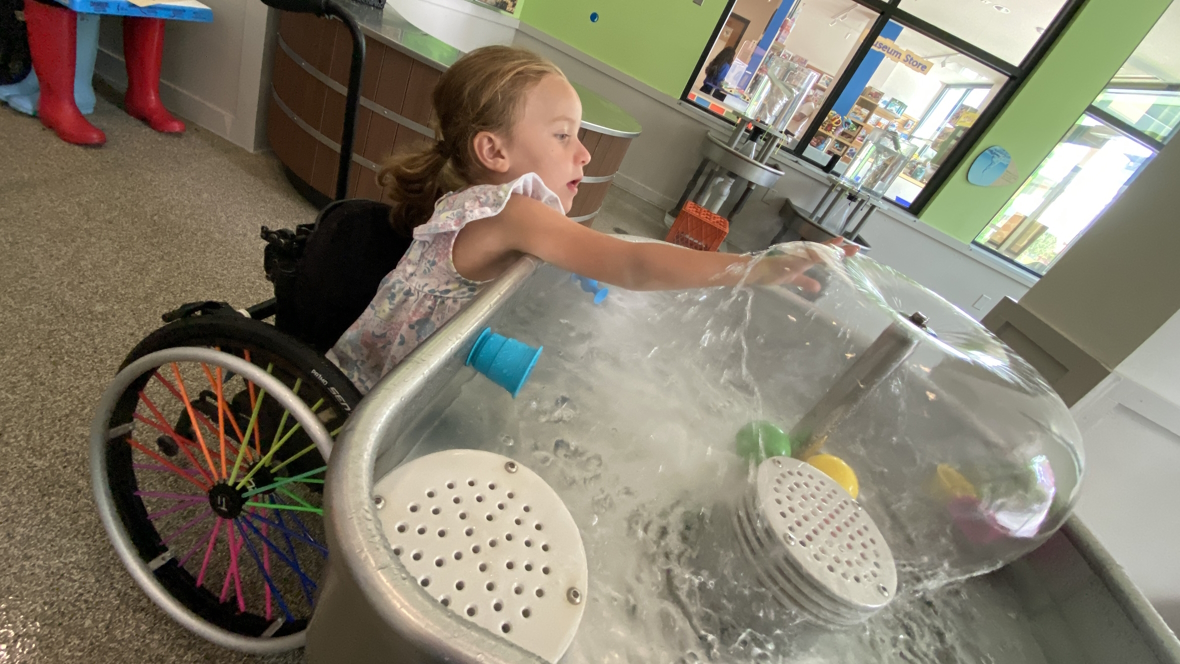 Girl in a wheelchair playing at a water table at KidsQuest Children's Museum