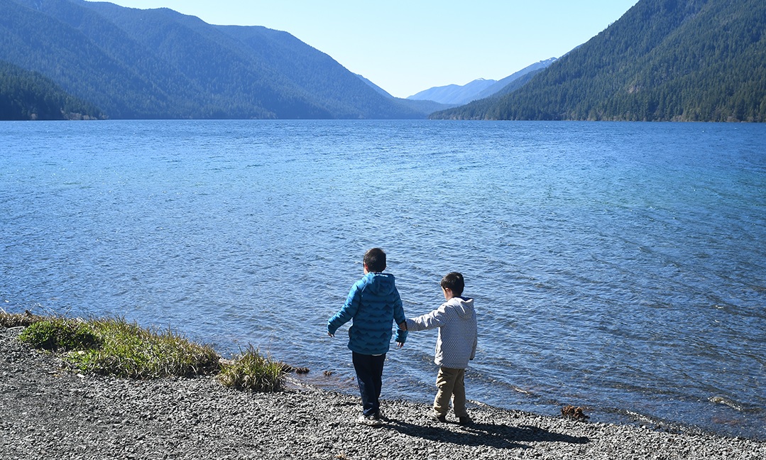 Brothers in jackets stand at the shore of Lake Crescent on Washington's Olympic Peninsula a getaway spot for Seattle-area families