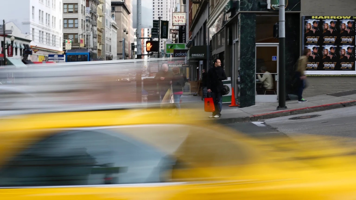 blurry image of a taxi cab driving down a busy city street