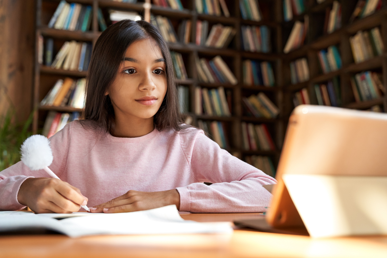 Young girl sits at a desk working on her homework