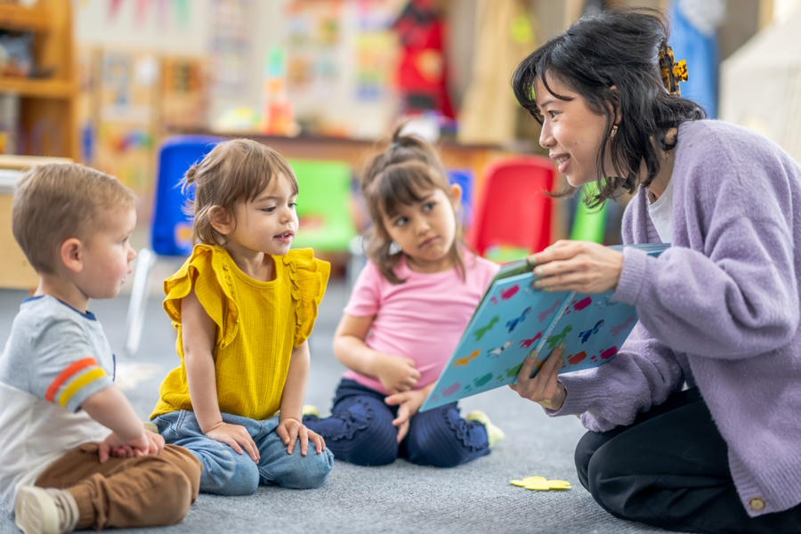 A co-op parent rading a book to a group of children in a classroom
