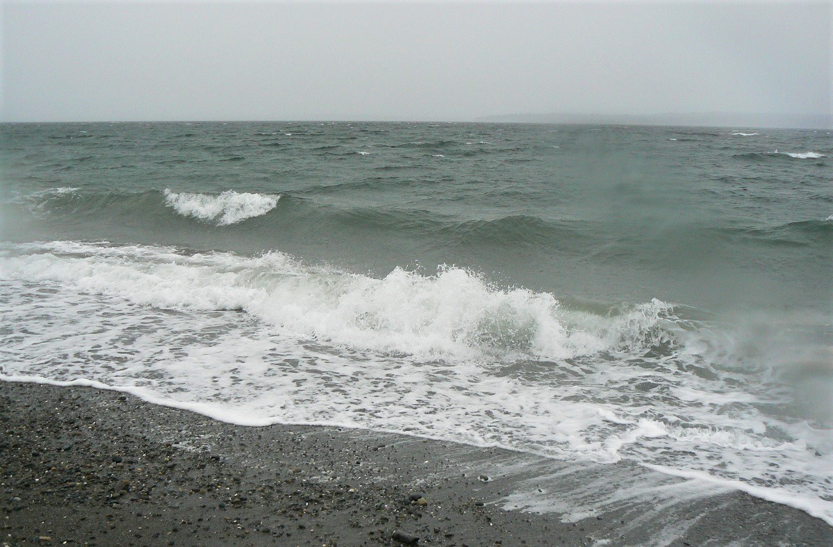 Waves breaking on the rocky shore of Marina Beach Park in Edmonds, Washington, near Seattle on a stormy, rainy, gray day