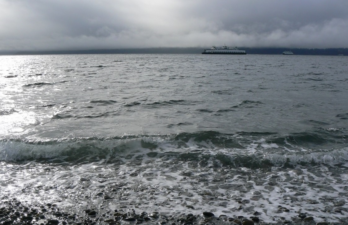 View of two state ferries from the shore of Lincoln Park in West Seattle on a cloudy, stormy day best places to experience stormy weather with kids around Seattle