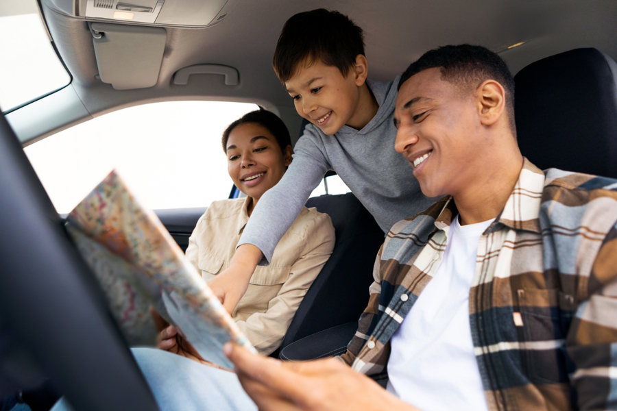 Boy and his parents look at a map on a family road trip