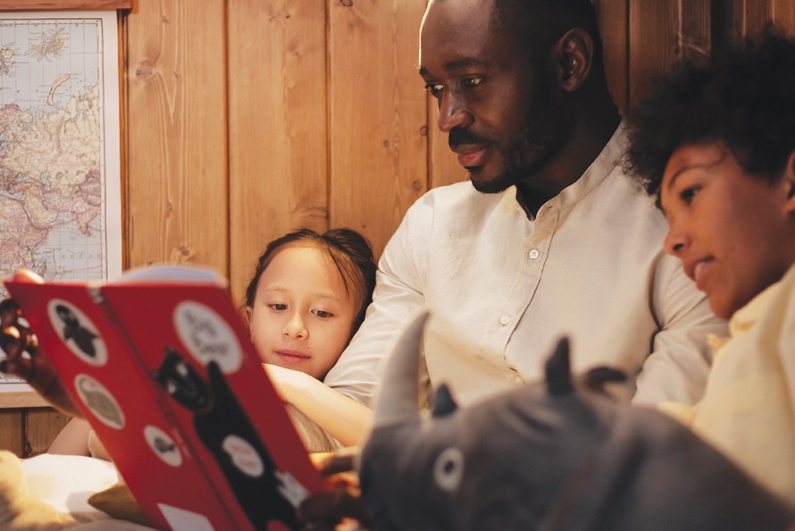 Dad sitting with kids reading a book