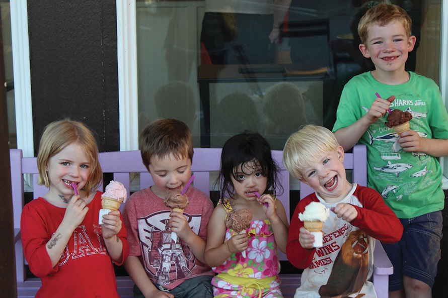 Kids eating ice crease and smiling on a purple bench