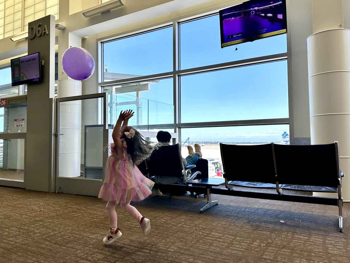 Little girl playing with a purple balloon at SEA airport