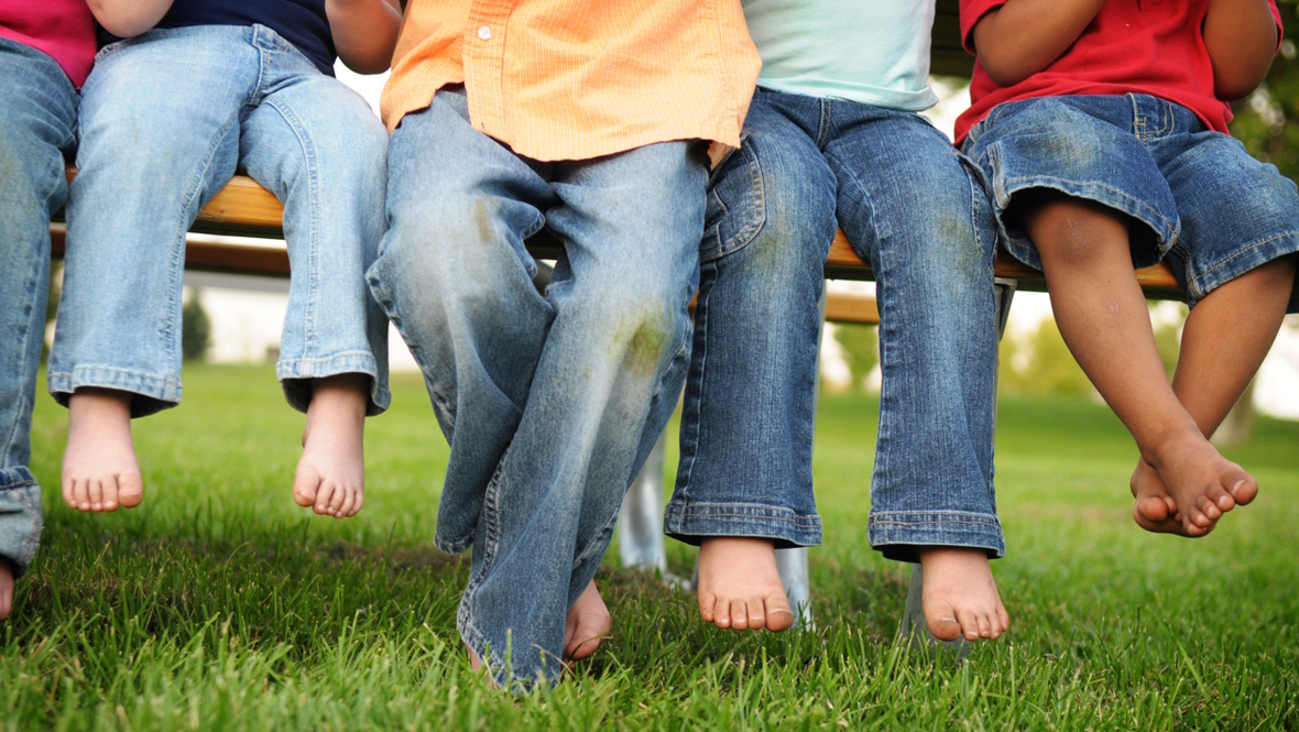 Young children sitting on a bench in the grass all wearing jeans. Target Denim Take Back Event