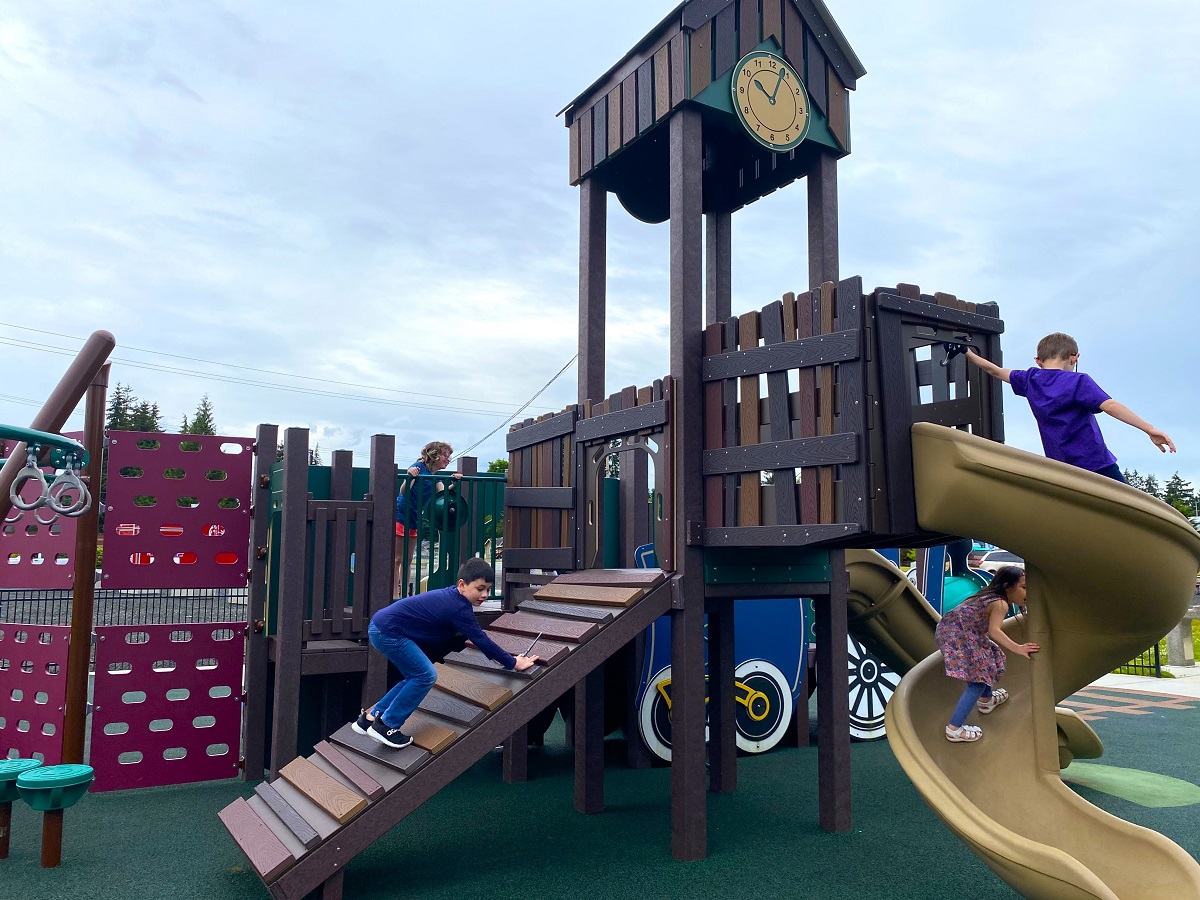 Kids play on the train themed playground at the new Lacey Depot District play area