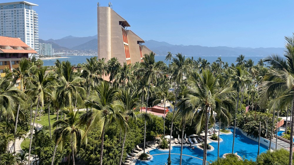 A Puerto Vallarta hotel with pools, palm trees and the Bay of Banderas in the background