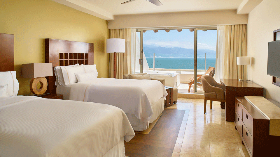 Two queen beds and a view of the ocean outside a hotel room in West Puerto Vallarta