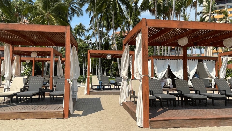 Wood framed cabanas on the sand with white curtains at the Westin Puerto Vallarta hotel