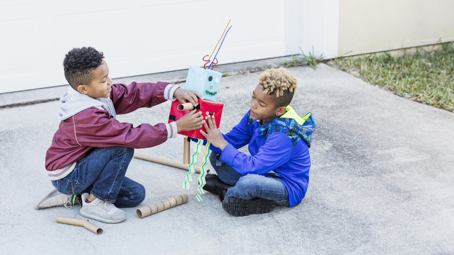 Two boys building a cardboard robot in a family competition based on a tv show