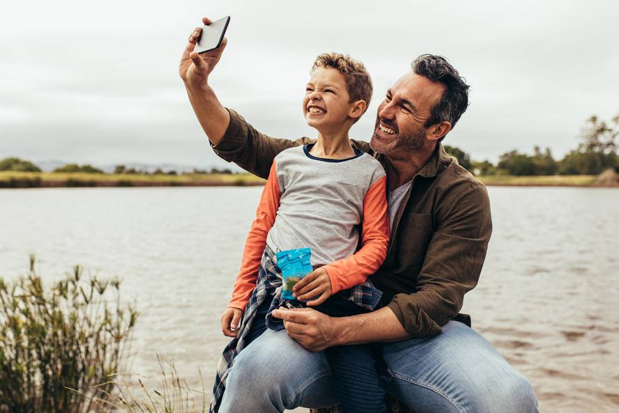 father and son taking a selfie outdoors