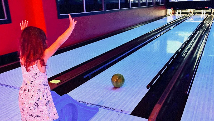 Young girl bowling with bumpers up at a Seattle bowling alley