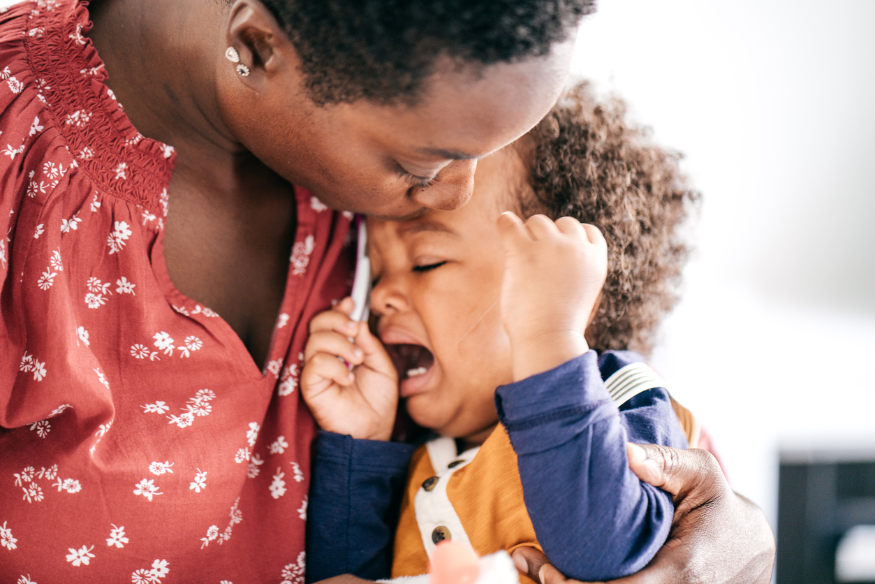 closeup of a mother kissing her tantruming screaming toddler