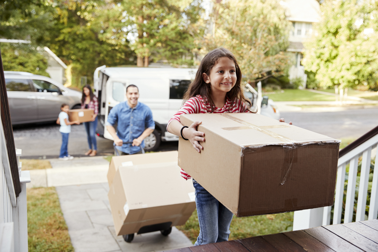 Young girl carrying a box into a house
