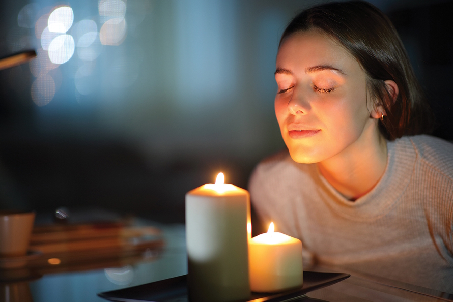 Woman smiling with her eyes closed with her face illuminated by candles 