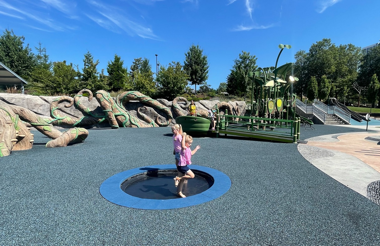 Girls jump on a trampoline feature at the inclusive Inspiration Playground at Bellevue Downtown Park things to do with kids in Seattle
