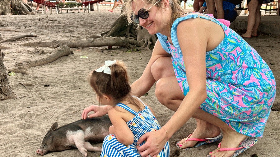mom and daughter petting a small pig on Pig Island in Thailand, a family-friendly activity