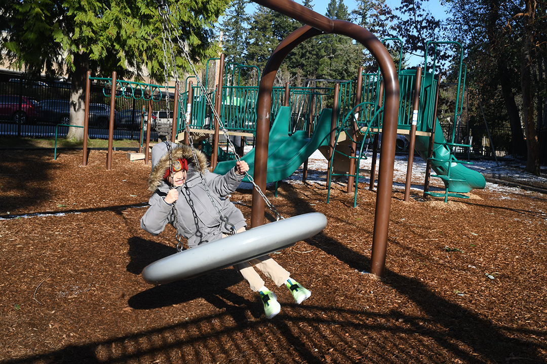 A boy swings on a tire swing at the waterfront park playground on Bainbridge Island's main town of Winslow easy ferry day trip for Seattle families with kids