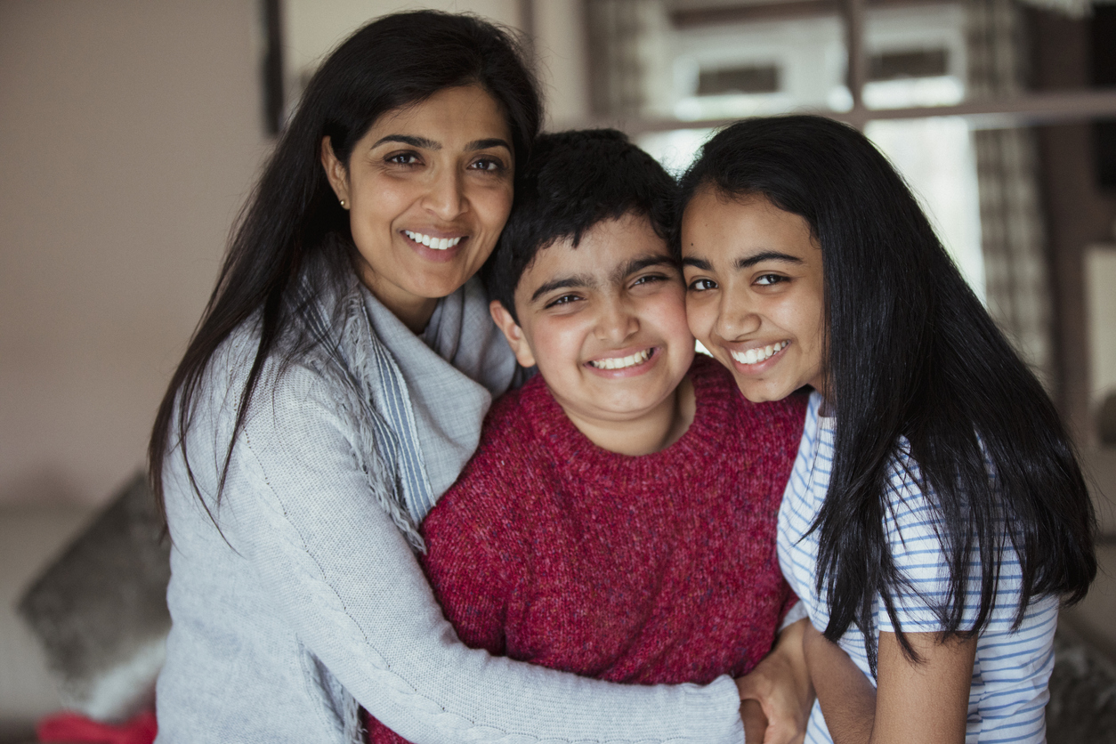 Boy hugged by sister and mother, all smiling