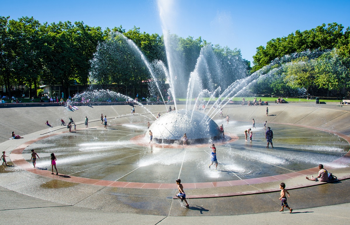 Kids play in the streams of water from Seattle Center's International Fountain on a fun summer day in Seattle
