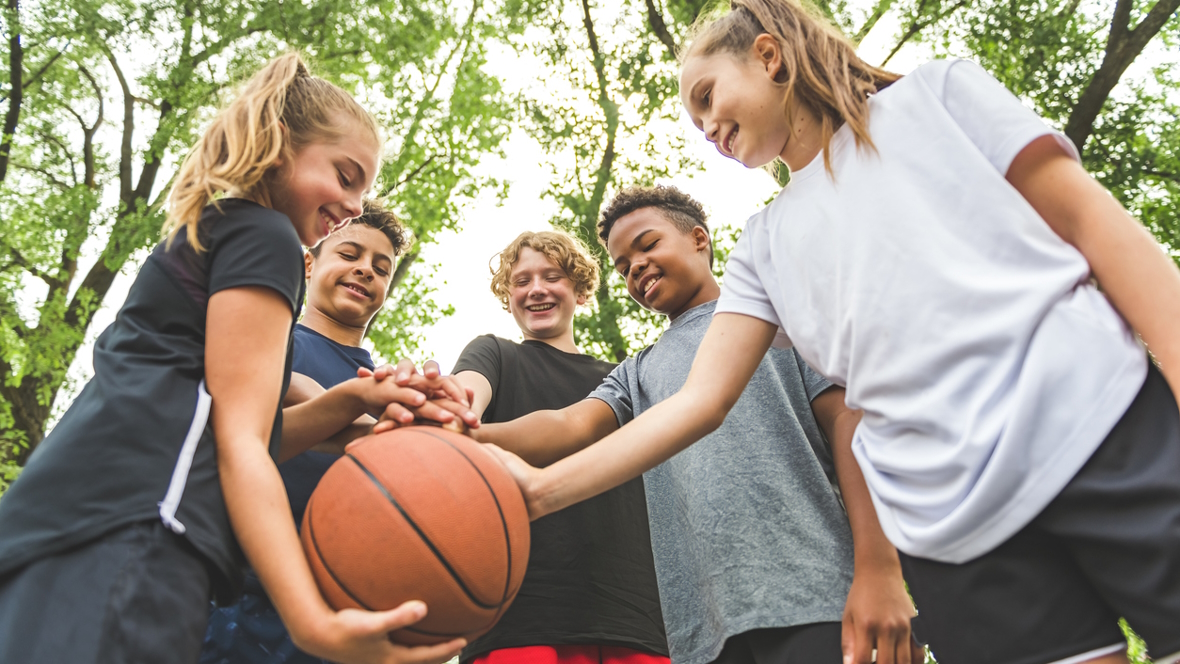 A group of kids holding a basketball and having fun playing a spring sports while staying injury-free thanks to tips from Seattle Children's hospital