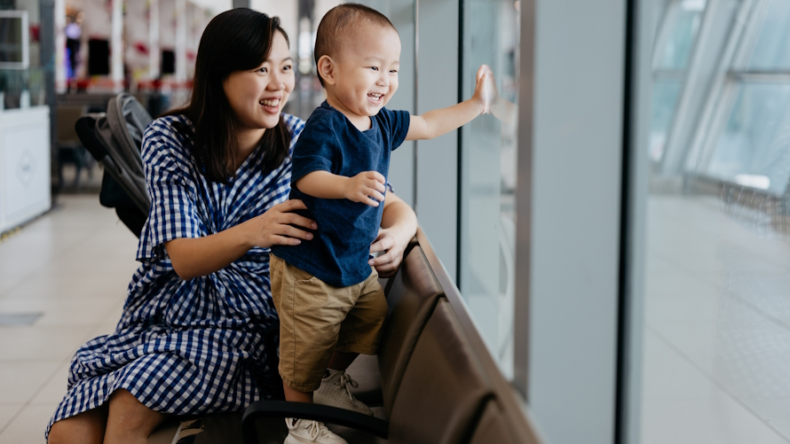 Cute baby smiling and looking out the windows at the airport with mom