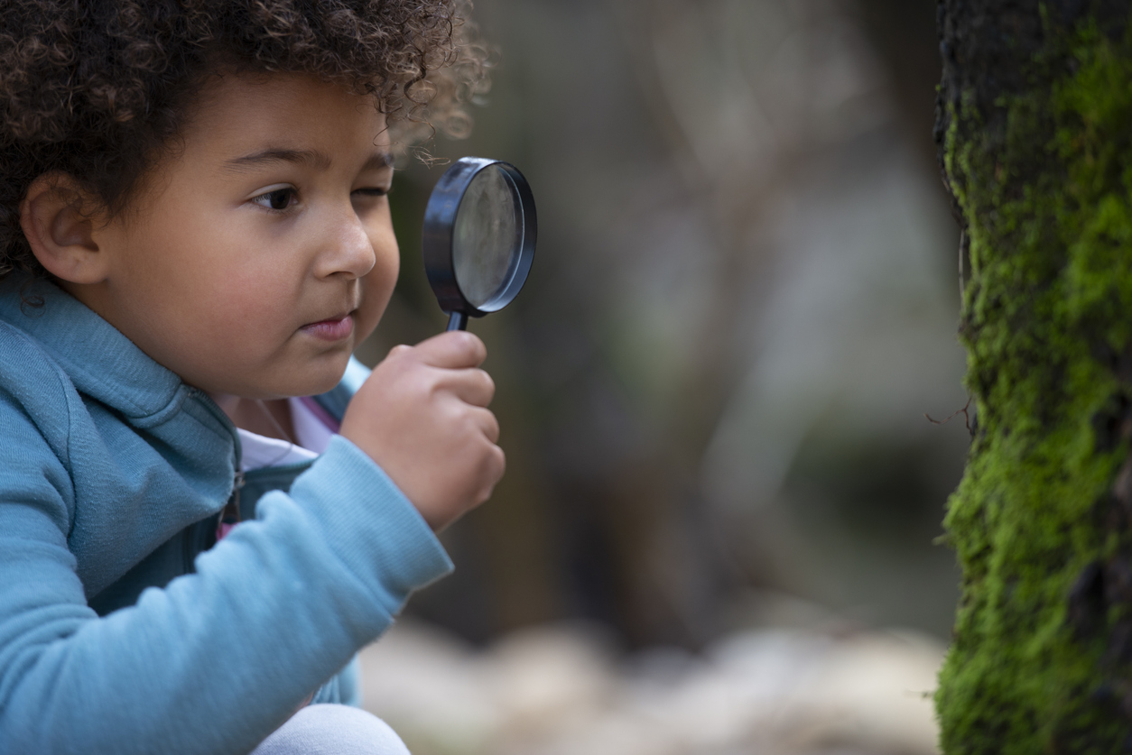 Child inspecting moss on tree with magnifying glass eco learning activities for home