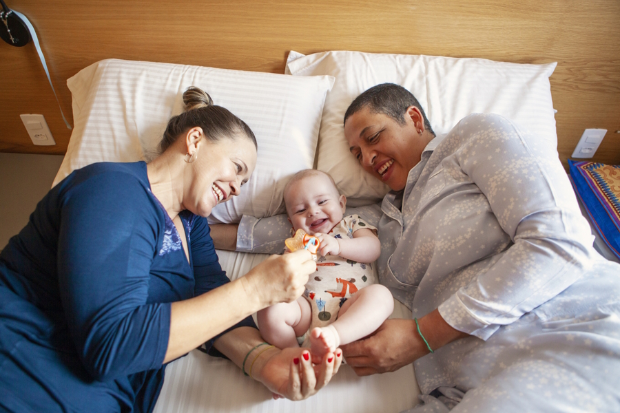 moms with baby in a bed giving positive environment five factors baby need to thrive