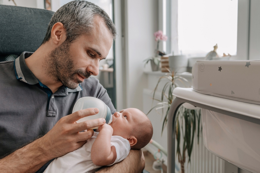 dad feeding his son five factors for babies to thrive