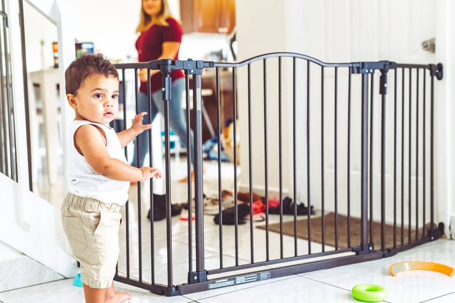baby standing next to a baby gate five factors for baby to thrive