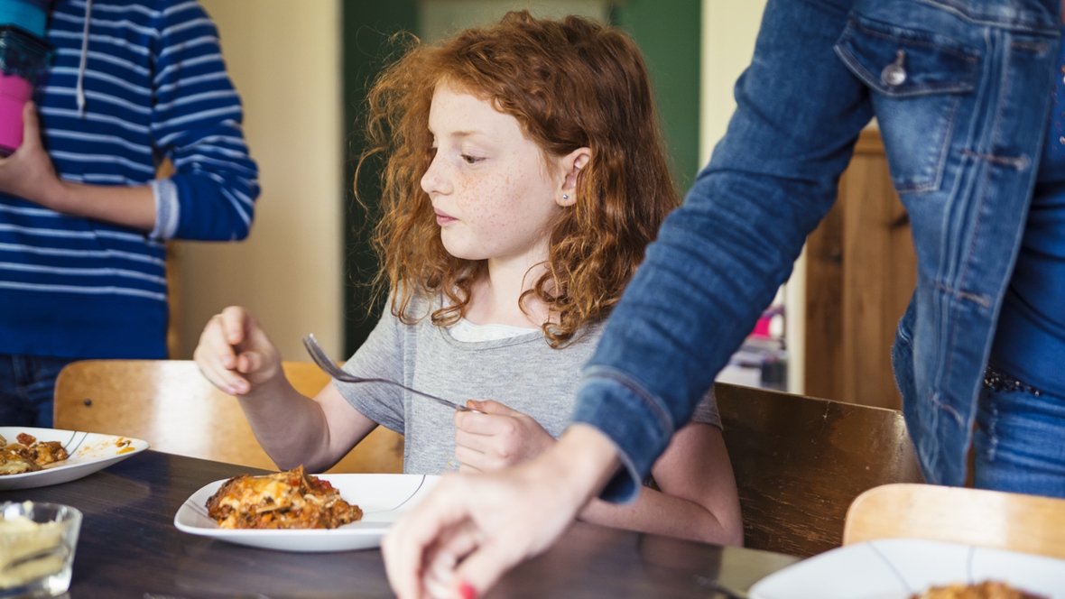 girl eating lasagna at home