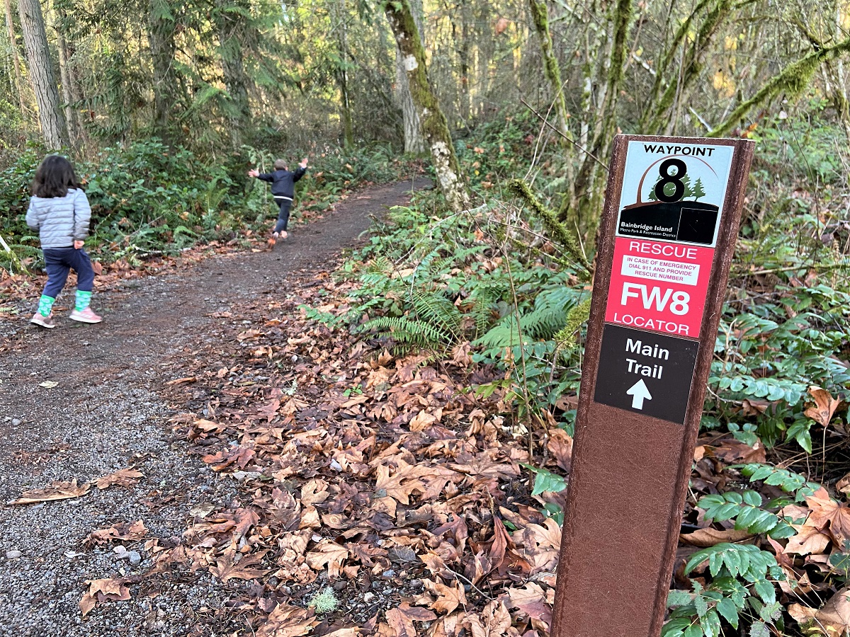 Kids on a hiking trail on Bainbridge Island passing a waypoint rescue finder sign