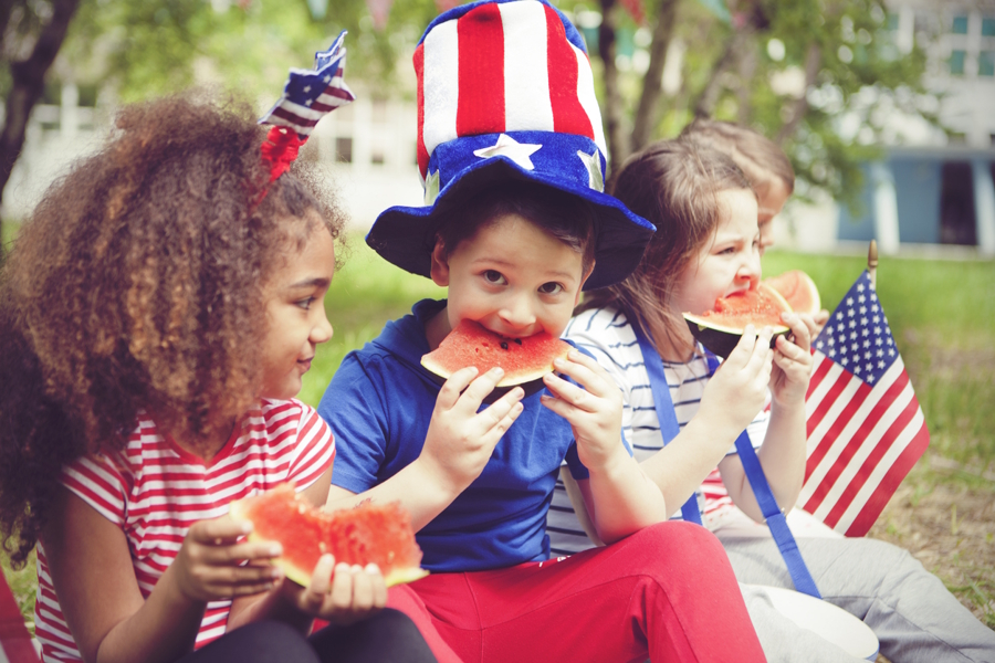 kids celebrating 4th of July at home with watermelon and hats with flags