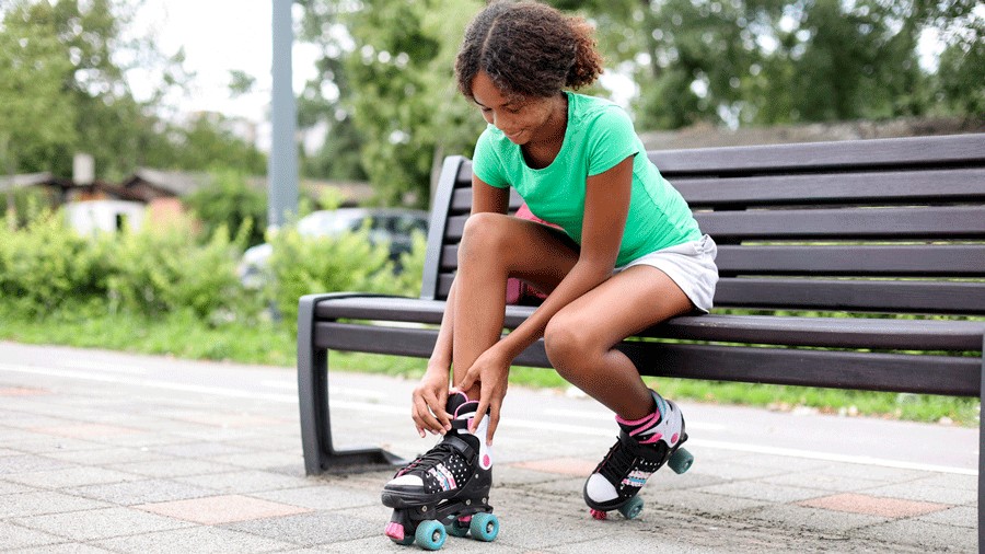 young girl lacing up roller skates at a Seattle park