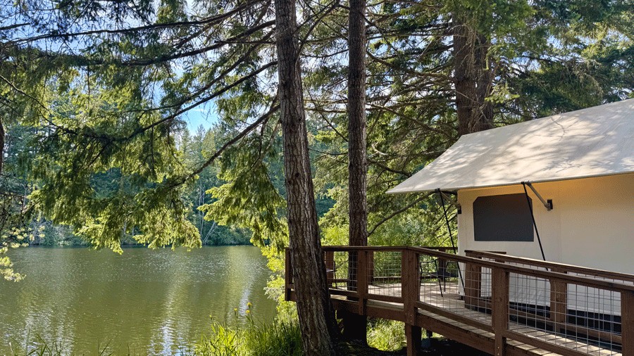 exterior view of Neva Lake Canvas Cottage, a glamping rental at Lakedale Resort, with a lake view and deck in front of the tent