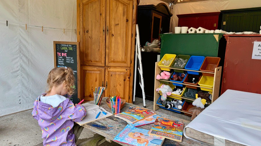 young girl wearing a raincoat coloring pages inside the activity tent at Lakedale Resort