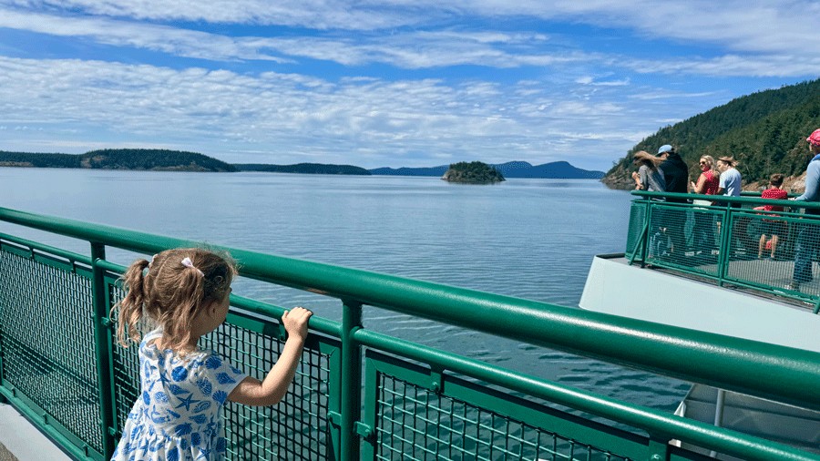 young girl taking in the scenic views of the water on the ferry from anacortes to friday harbor for a family glamping trip
