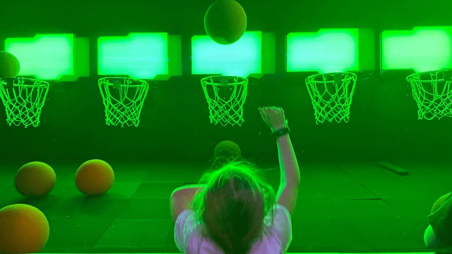 young girl shooting basketball hoops at C.H.E Arcade