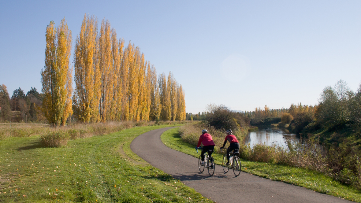 Two people on a bike ride on a kid-friendly hiking trail near Seattle along a river