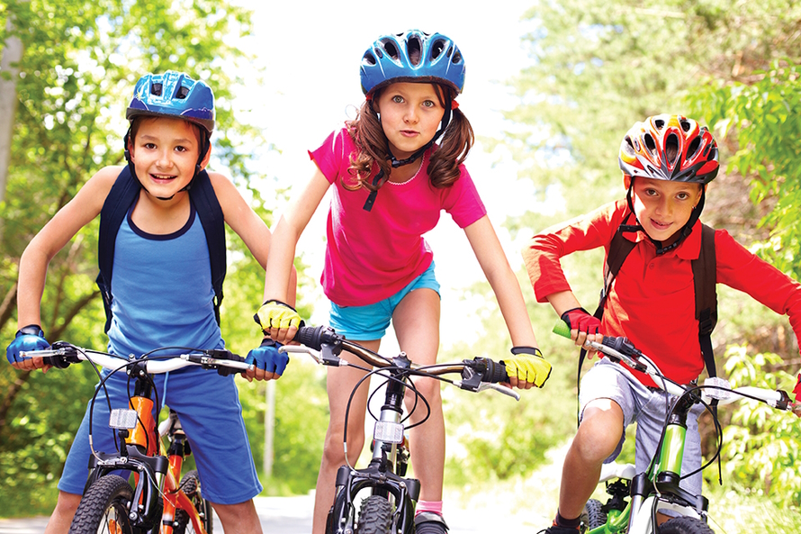 Three kids on bikes wearing shorts and t-shirts