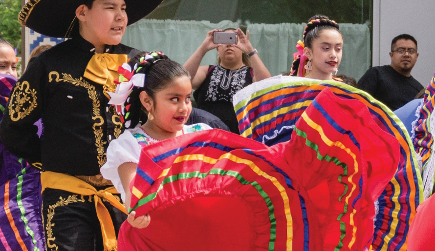 Young girls in traditional Mexican clothing dancing