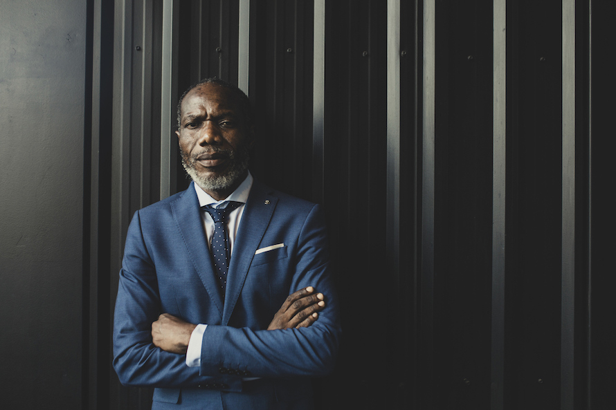 dapper man in a suit smiles lightly looking at the camera