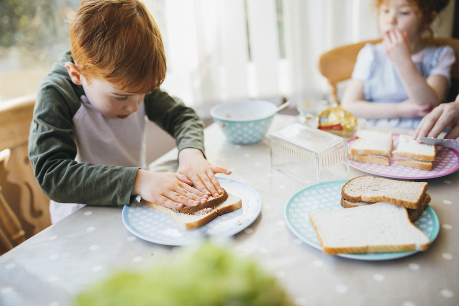 school-age boy makes his own sandwich for lunch