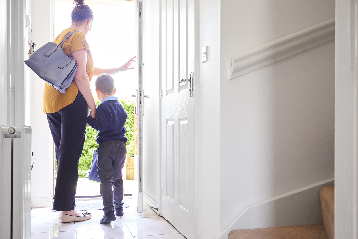 mother and son walking out the front door on the first day of school
