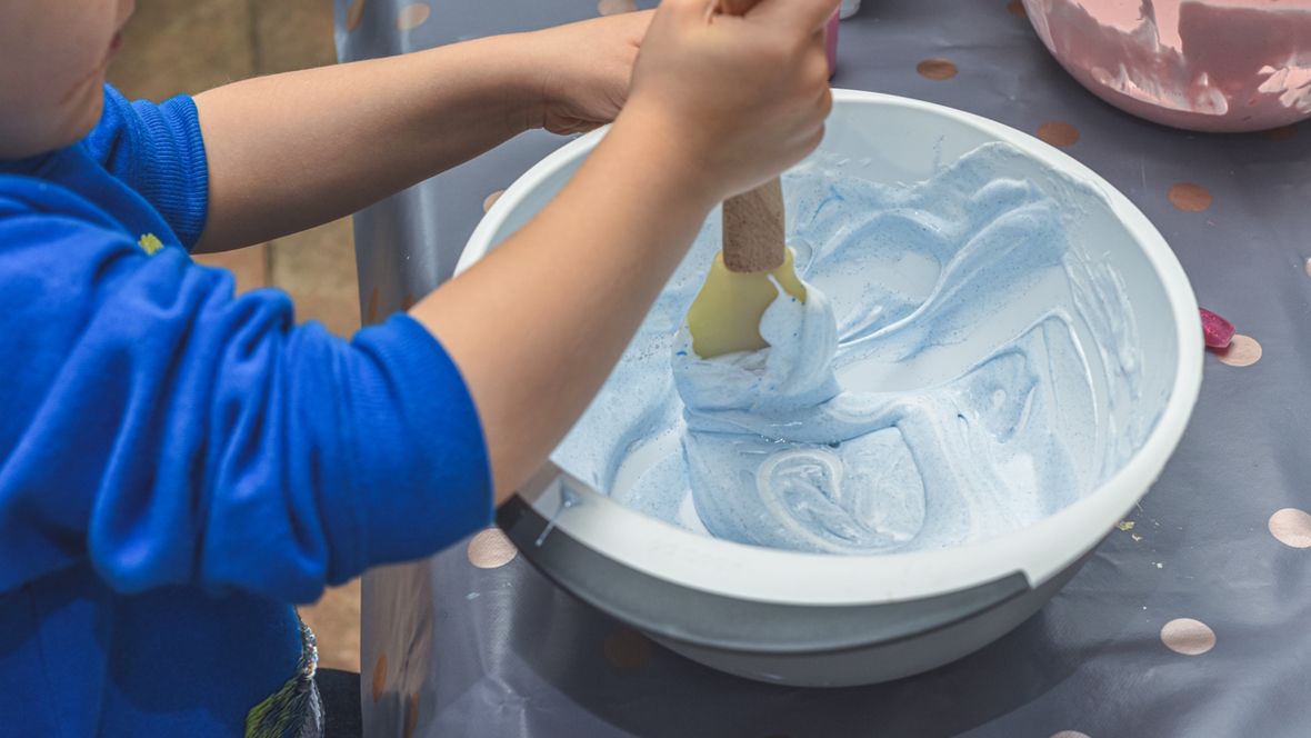 child mixing shaving cream and food coloring