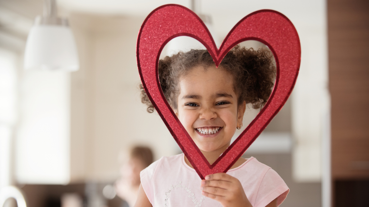 Little girl holding a heart shape around her head
