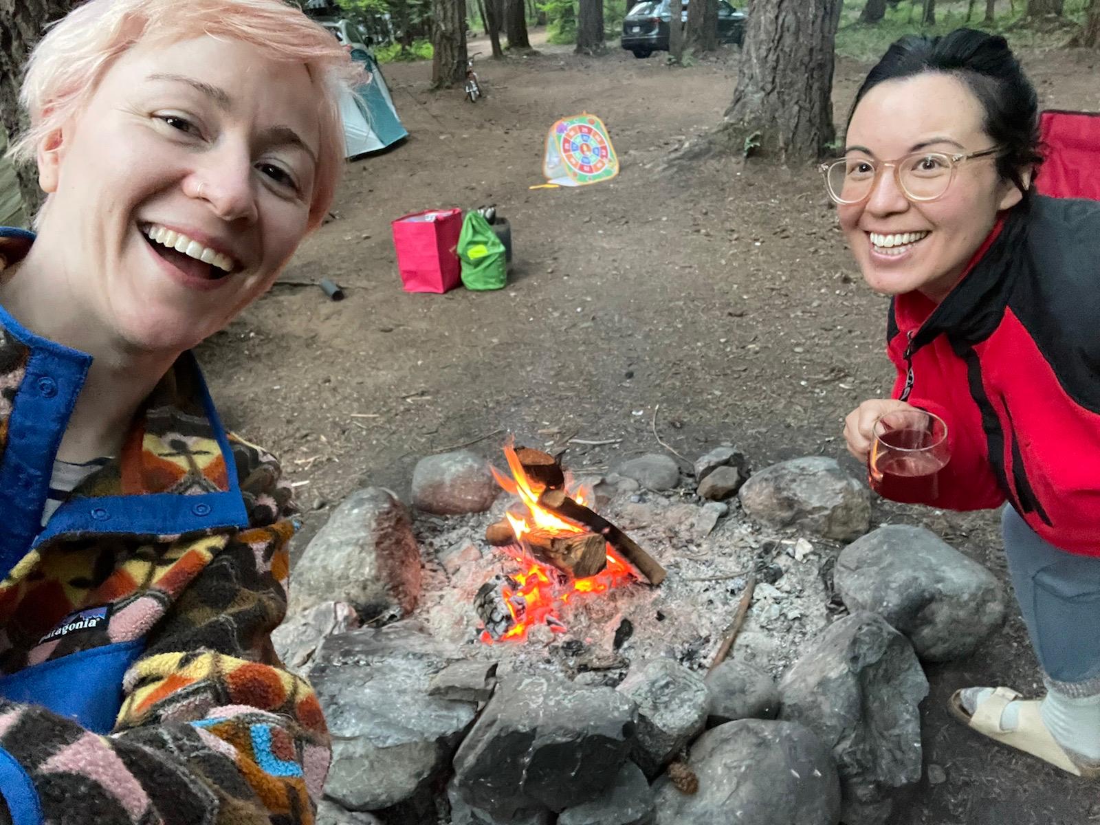 Two mom friends smile for a selfie while camping.